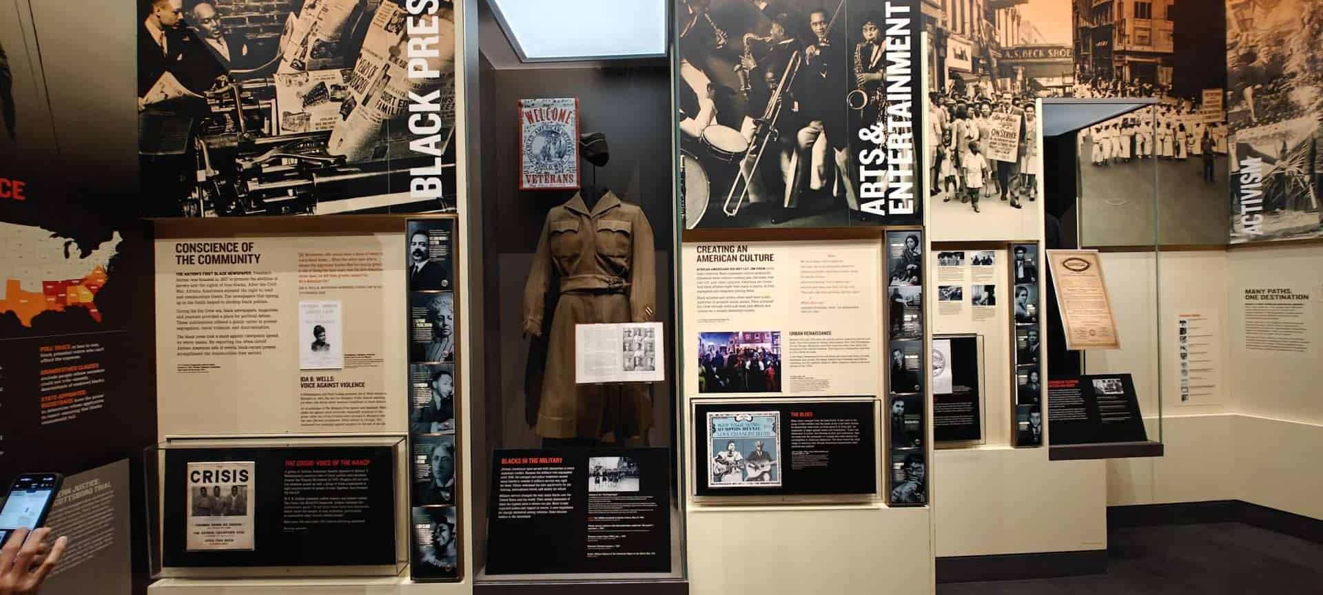 Gallery walls at the National Civil Rights Museum in Memphis with Black Press and Arts and Entertainment exhibit panels and a uniform on display.