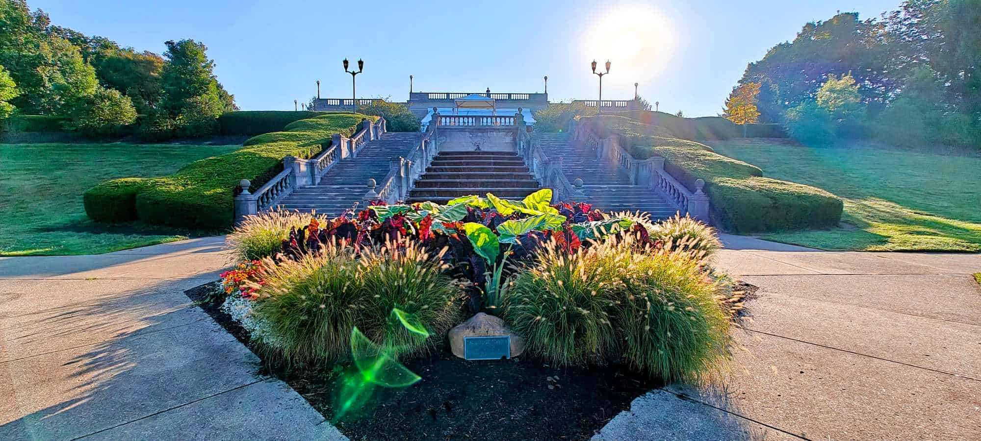 Beautiful view of Ault Park in Cincinnati, Ohio, featuring lush greenery, colorful flower beds, and a grand staircase leading to the park's overlook.