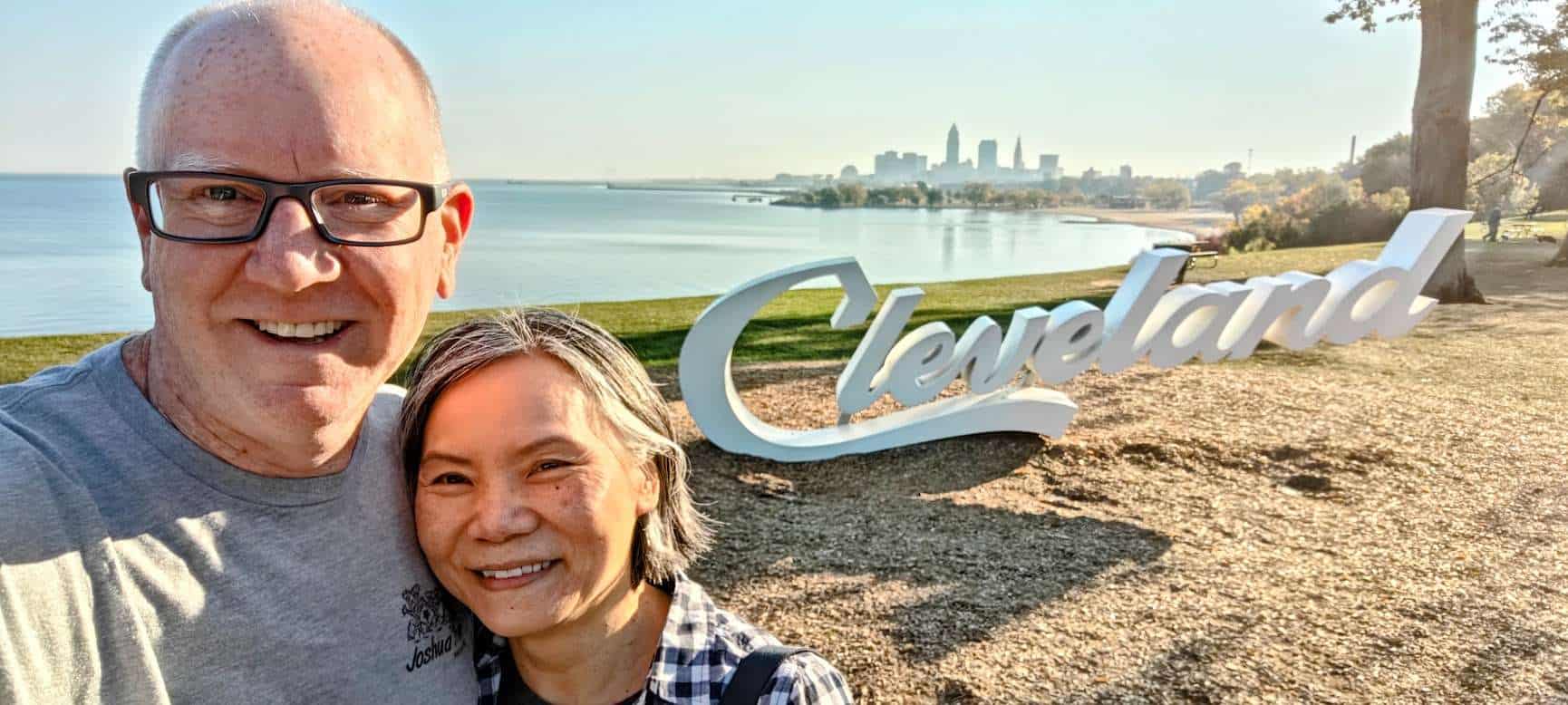 John and Vi taking a selfie in front of the Cleveland script sign with Lake Erie and the skyline behind them