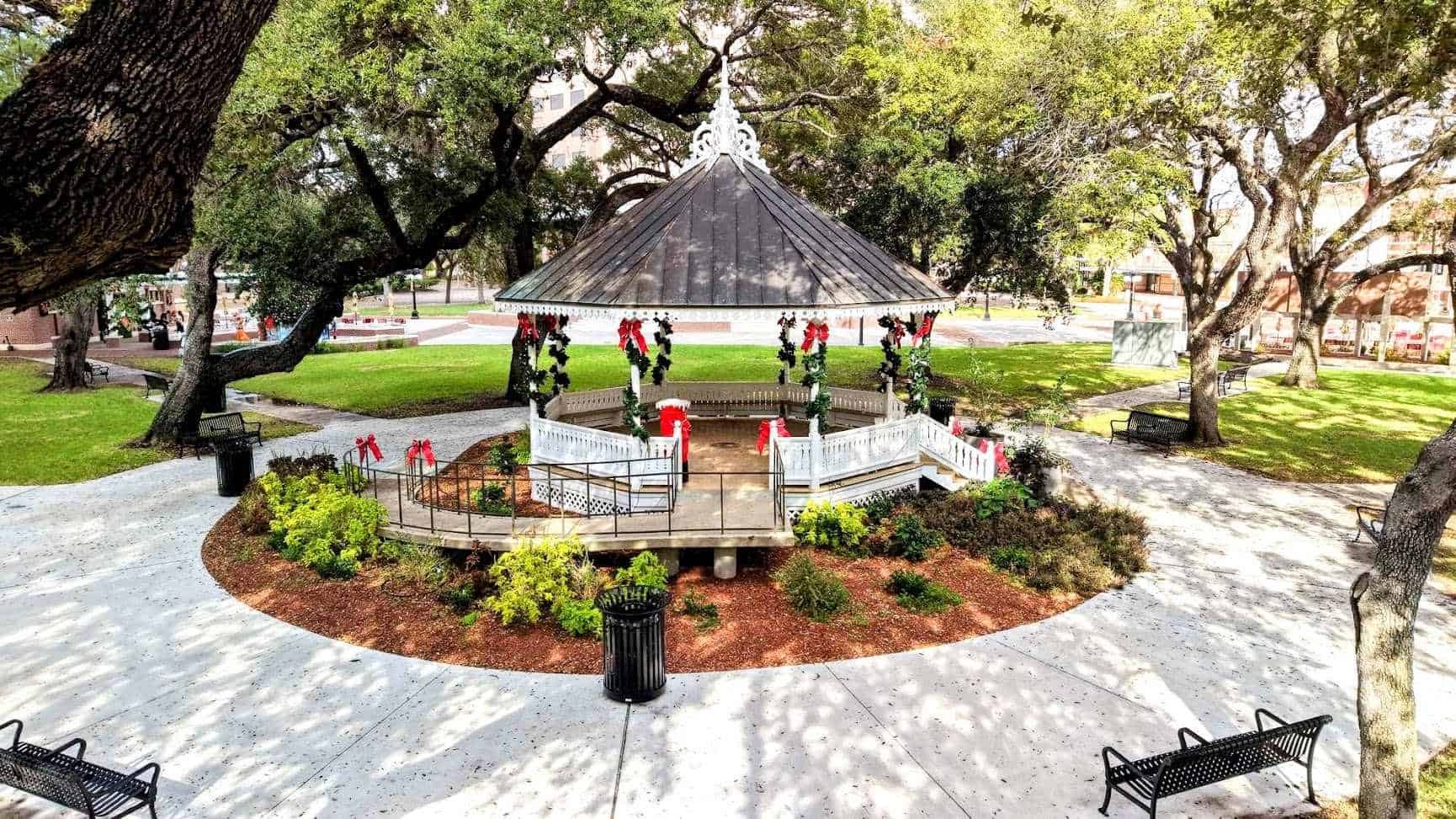 White Victorian bandstand decorated with Christmas garland and red bows at DeLeon Plaza in Victoria, Texas